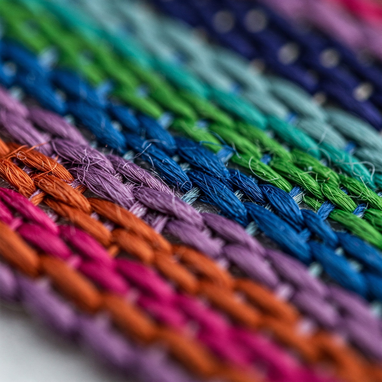 Close-up macro photograph of colorful embroidery thread skeins arranged in rows showing rainbow gradient