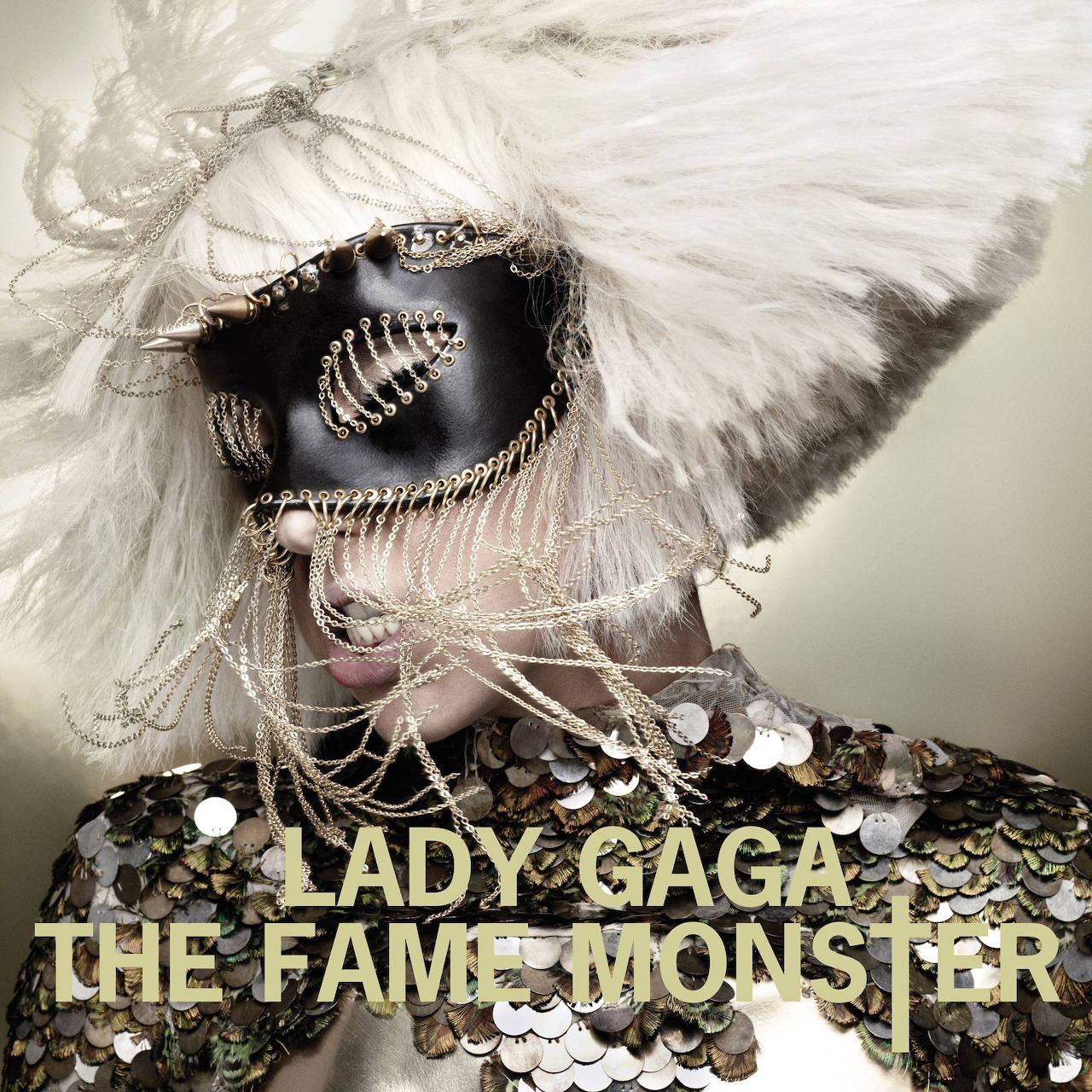 Lady Gaga in a black mask and white feather headpiece above The Fame Monster text