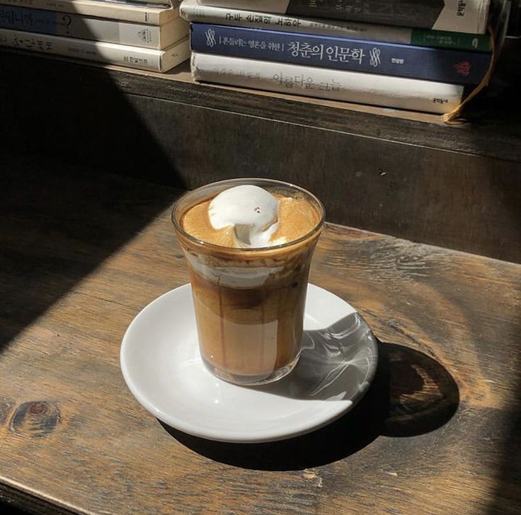 Glass of layered affogato coffee with ice cream on a white saucer on a wooden table