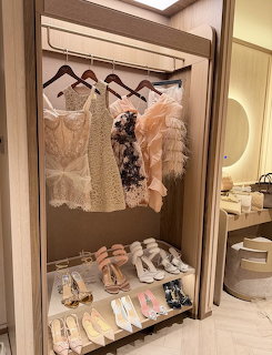 Open wardrobe with pink and neutral dresses on hangers and a row of shoes arranged below