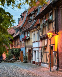 Traditional half-timbered buildings on cobblestone street in Quedlinburg with colorful facades and vintage street lamp