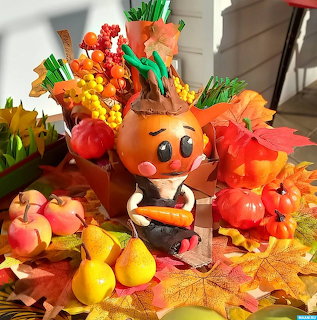 Handmade pumpkin figure surrounded by autumn leaves, pears, and small pumpkins