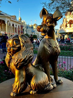 Bronze statue of two dogs from Lady and the Tramp at Disney park entrance with castle in background