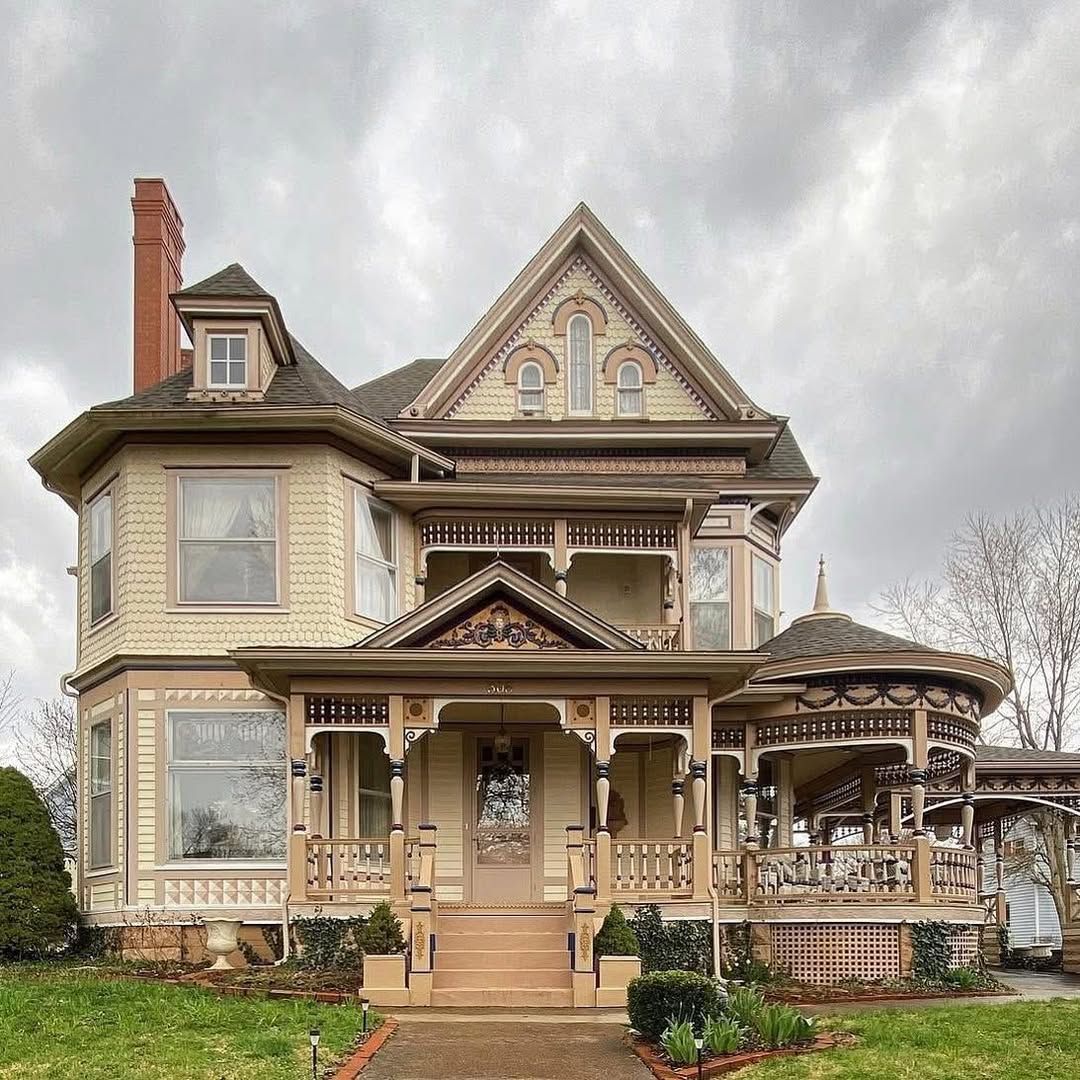 Ornate Victorian house with wraparound porch and turret under stormy sky