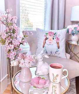 Pink-themed living room with Easter bunny decorations, flowers, macarons, and coffee mug on table