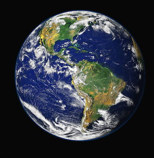 Planet Earth from space showing the Americas with blue oceans, green continents, and white clouds on black background