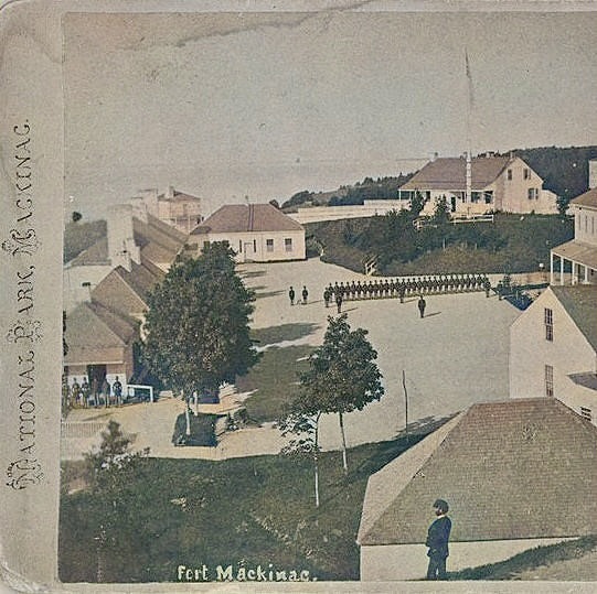 1880 tinted stereoview of Fort Mackinac parade ground with buildings, soldiers, and trees