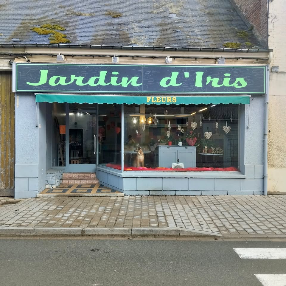 Small flower shop storefront with display windows and a green Jardin d'Iris sign