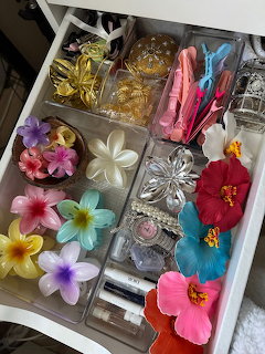 Open white drawer with colorful tropical flower hair clips and accessories in clear organizer compartments