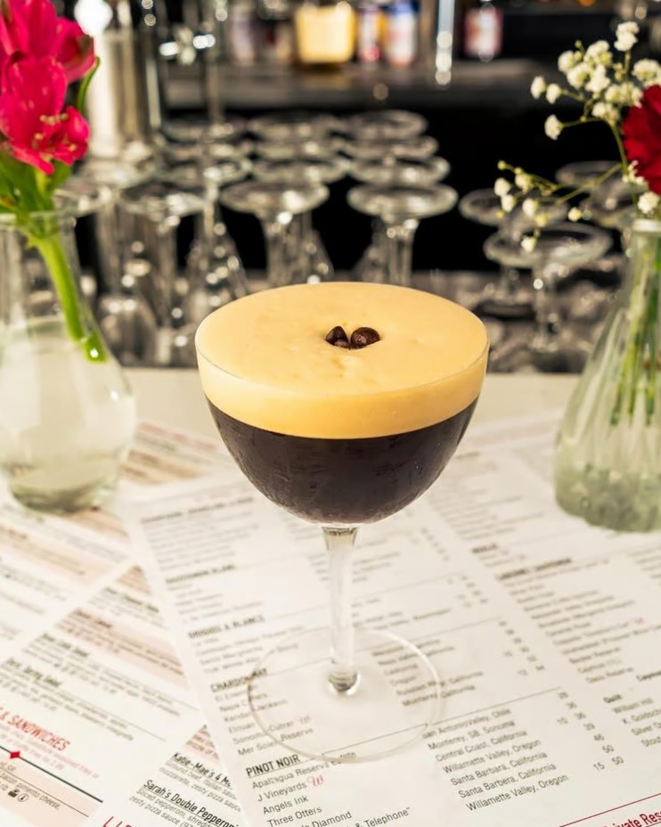 Espresso martini in a stemmed glass with creamy foam and a coffee bean garnish on menus