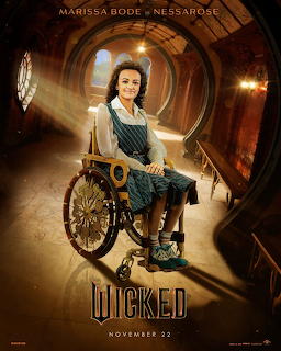 Woman in teal dress seated in ornate wheelchair inside circular golden chamber