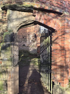 Old brick and stone doorway with an iron gate in a ruined passage