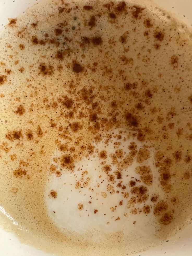 Top-down view of a chai latte with cinnamon sprinkled on foamy surface
