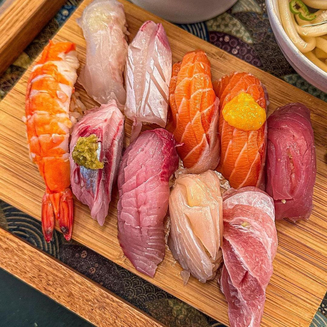 Assorted nigiri sushi pieces with salmon, tuna, shrimp and fish on wooden serving board