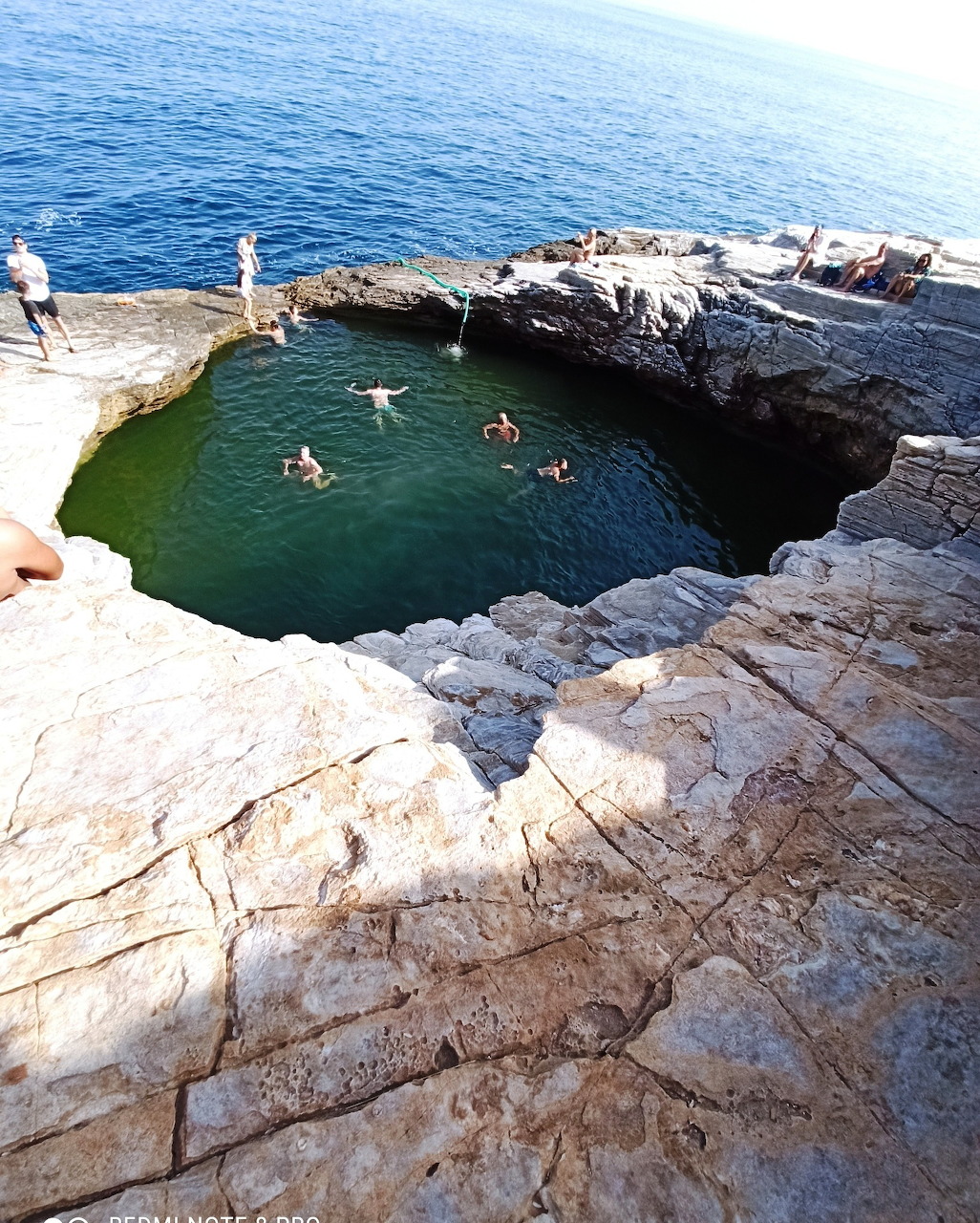 Natural rock pool at Giola in Thasos with swimmers, rocky cliffs, and the sea beyond