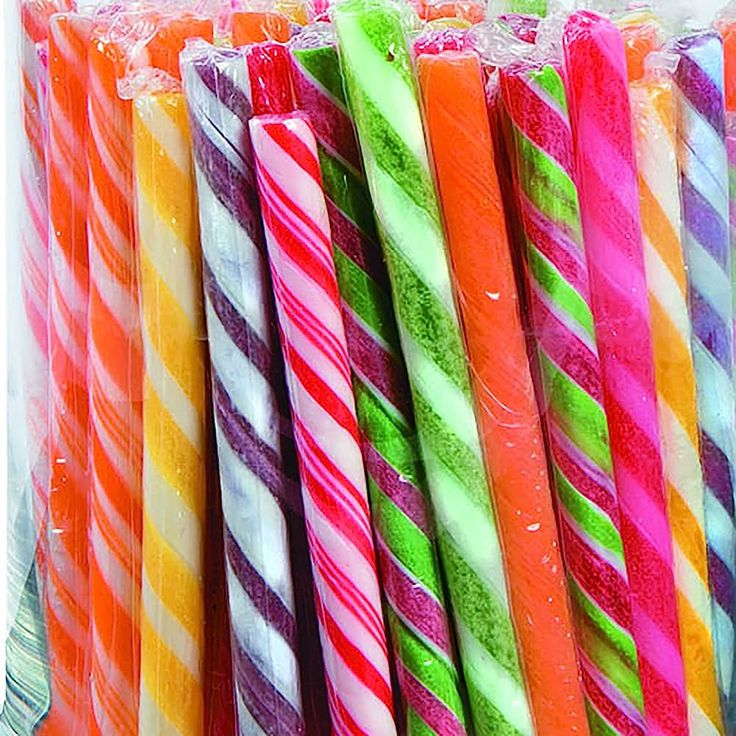 Assorted colorful striped candy sticks wrapped in clear cellophane arranged vertically