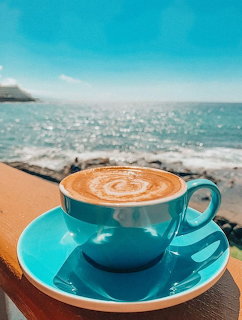 Turquoise coffee cup with latte art on wooden table by the ocean