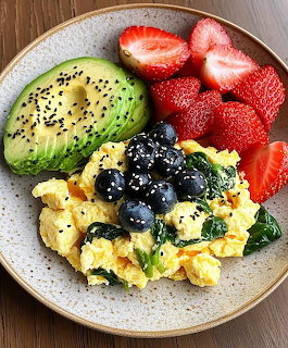 Breakfast plate with eggs, avocado, strawberries and blueberries on ceramic plate