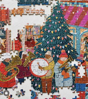 Partially assembled jigsaw puzzle showing a cheerful Christmas market scene with a decorated tree and children