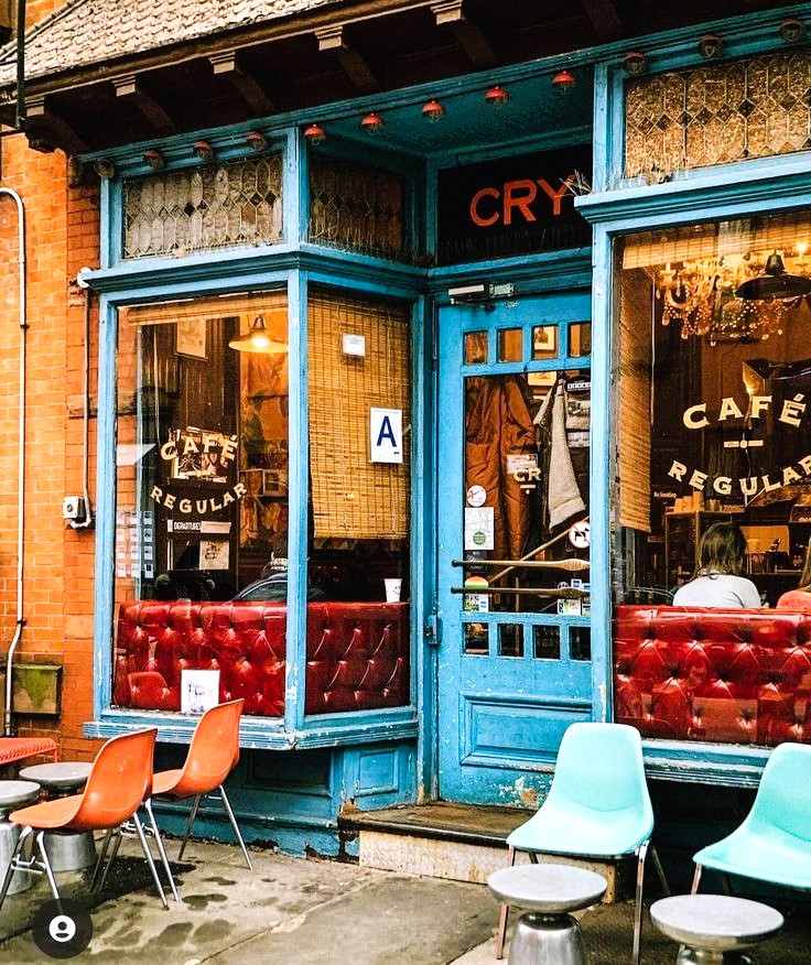 Turquoise cafe storefront with red tufted benches, outdoor seating, and vintage signage on brick building