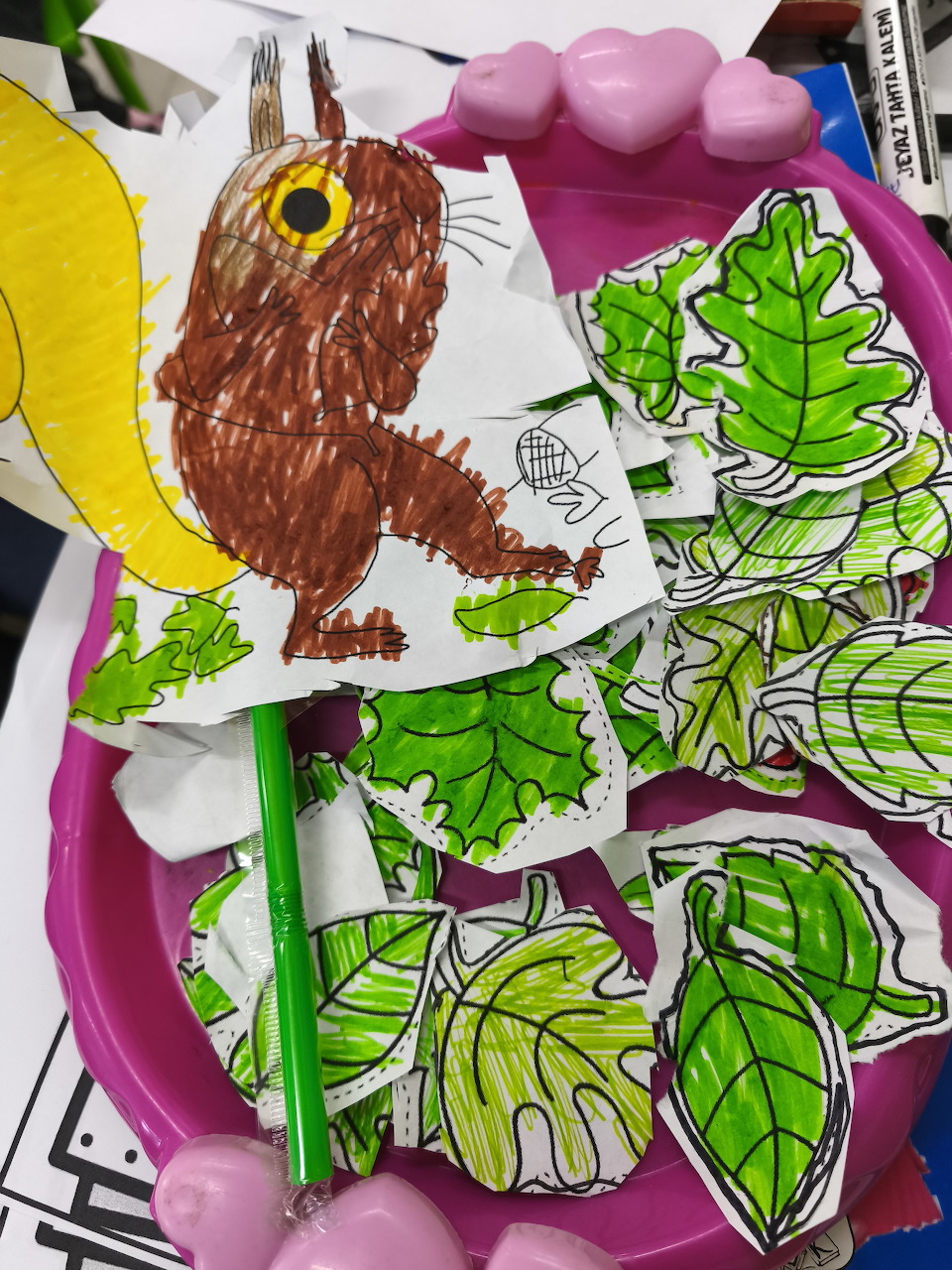 Hand-drawn Gruffalo figure and cut-out green leaf shapes arranged on a pink plastic tray