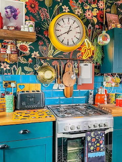 Bright bohemian kitchen with yellow clock, turquoise cabinets, and floral wallpaper with eclectic decor