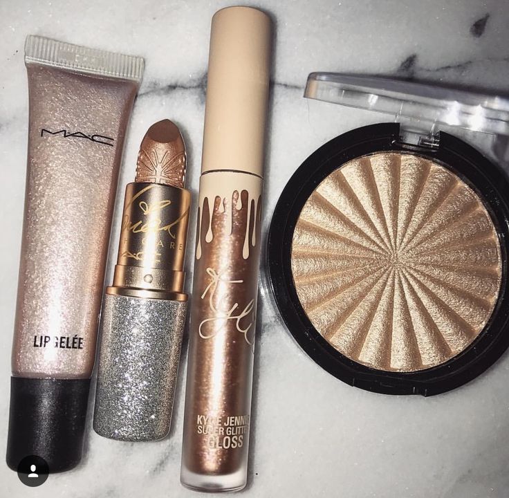 Gold makeup items including lip gloss, lipstick, and highlighter on a white background