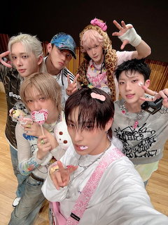 Six young men from K-pop group P1Harmony posing together for a group selfie indoors
