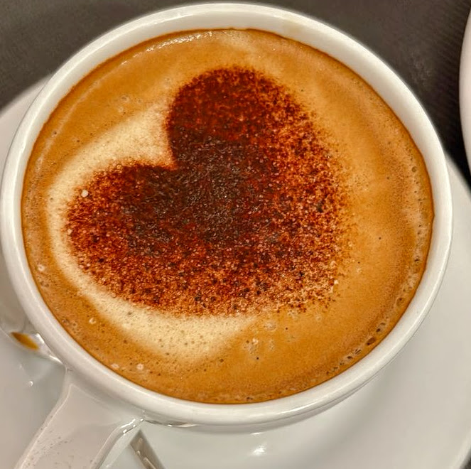 Cup of latte with a heart-shaped cocoa design on the foam