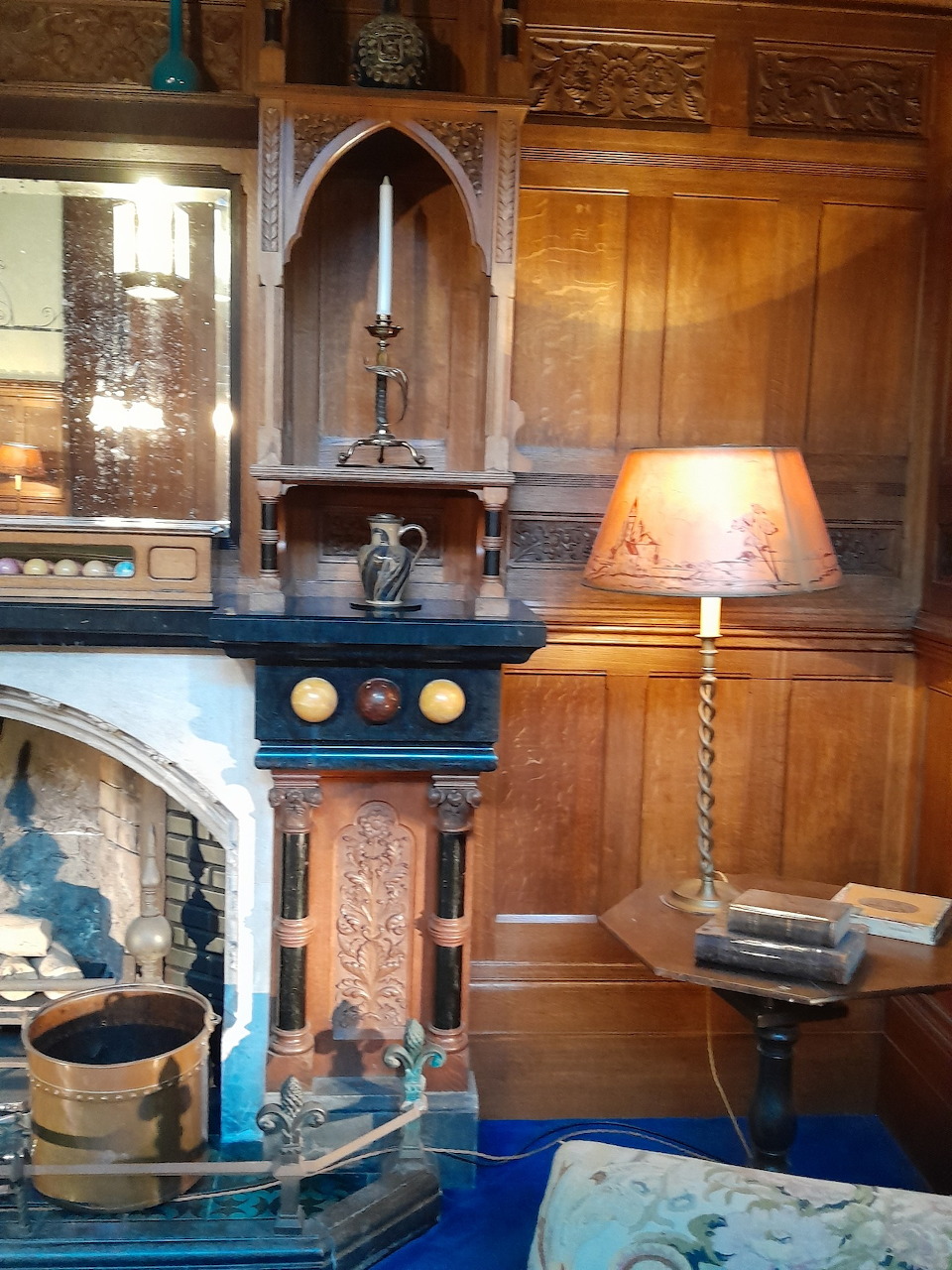 Victorian billiard room with wood paneling, ornate fireplace, and period lamp