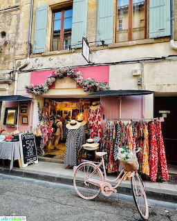 Pink boutique with vintage bicycle and clothing racks on French street