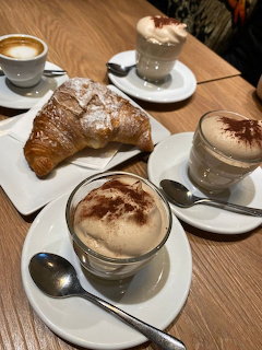 Croissant and frothy coffee drinks on a wooden cafe table