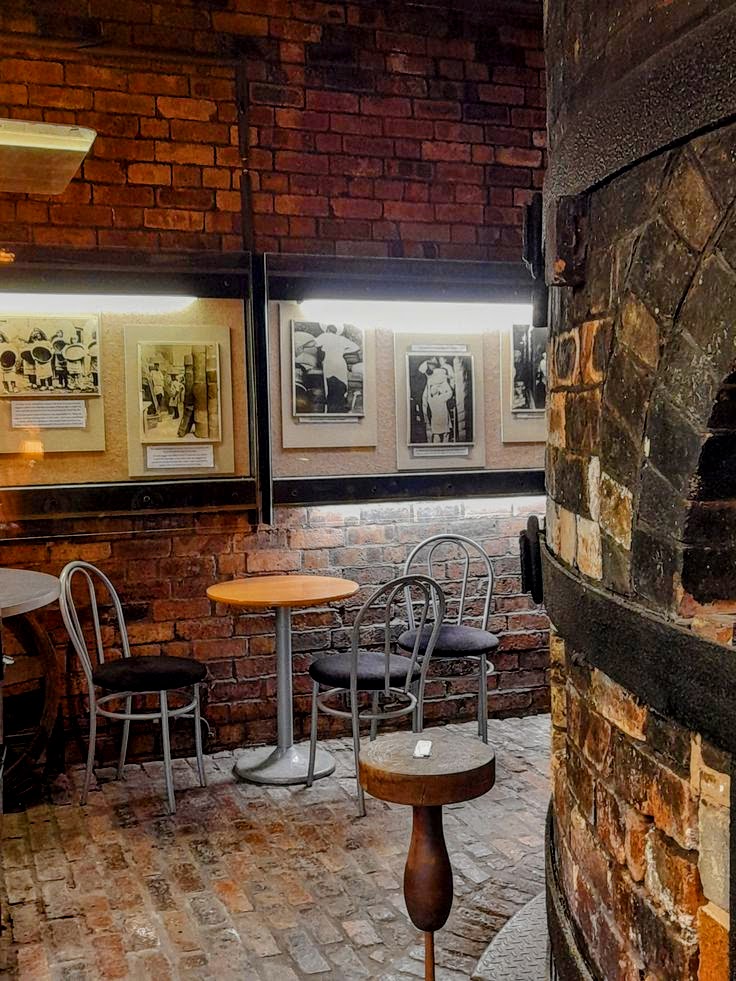 Cozy cafe interior with brick walls, small tables, metal chairs, and framed black-and-white photos