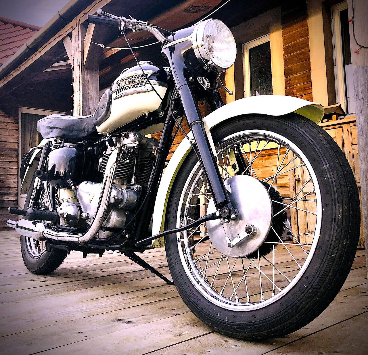 White 1959 Triumph Tiger 100 vintage motorcycle on wooden porch