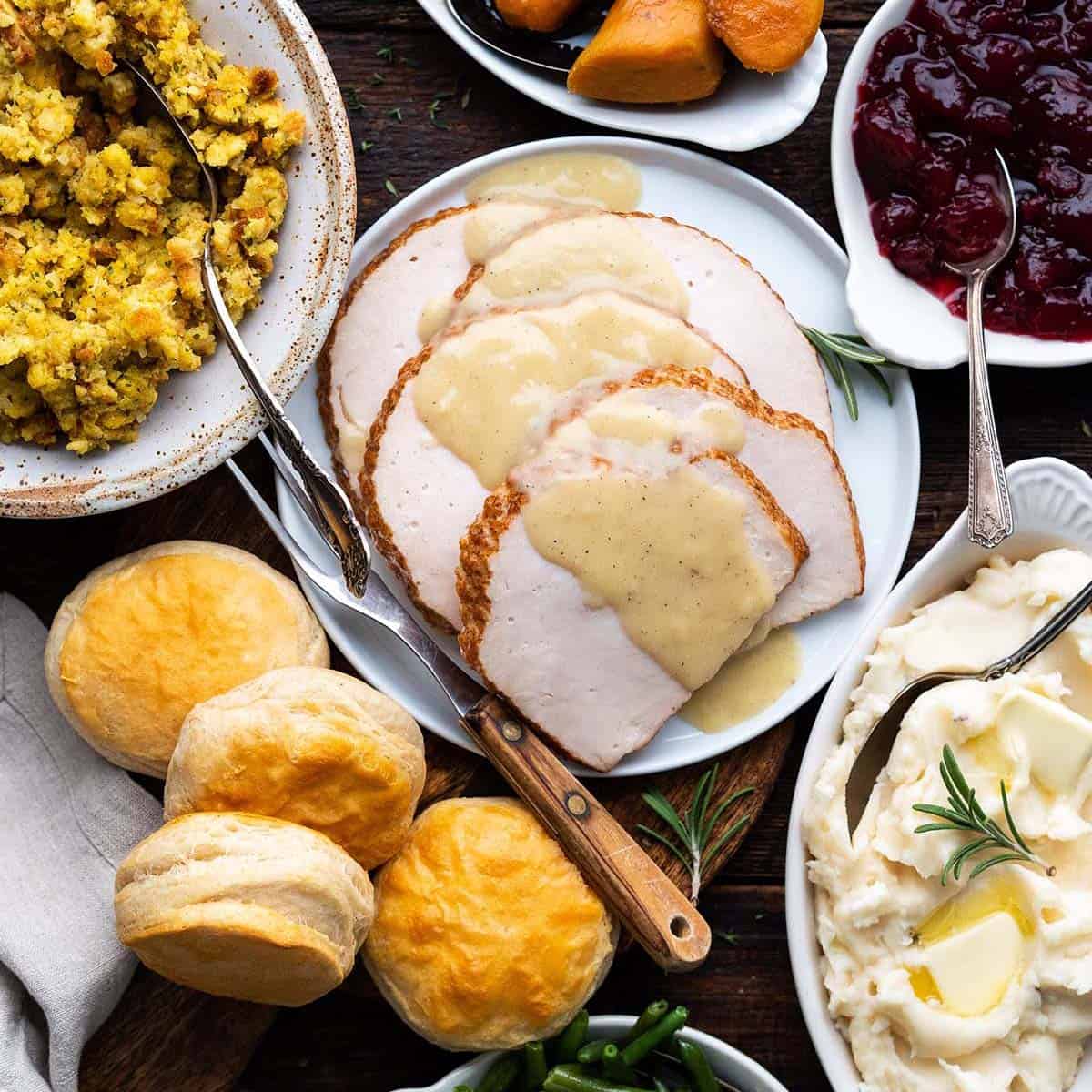 Overhead view of Thanksgiving dinner with turkey, sides, and cranberry sauce on white plates