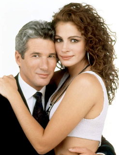 Man with silver hair in suit embracing woman with curly auburn hair in white top