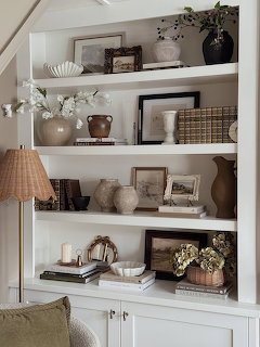White built-in bookshelf with styled decor including vases, frames, books, and a floor lamp