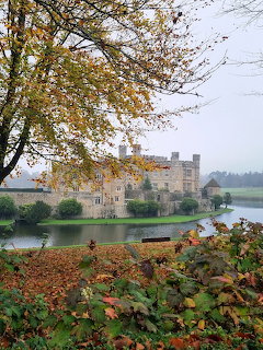 Leeds Castle across moat in autumn with tree branches in foreground