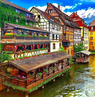 Traditional half-timbered buildings along a canal in Strasbourg, France with vibrant colors and reflections