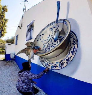 Person beside a large teacup mural on a white and blue outdoor wall
