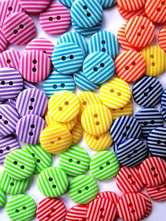 Assortment of colorful round striped buttons in various bright colors scattered on a white background