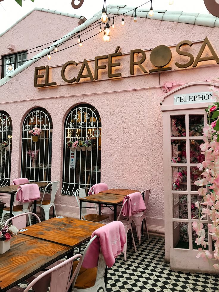 Pink exterior of El Café Rosa with outdoor tables, arched windows, and a white telephone box