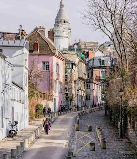 Coblestone street in Montmartre Paris with colorful buildings and Sacré-Cœur dome in background