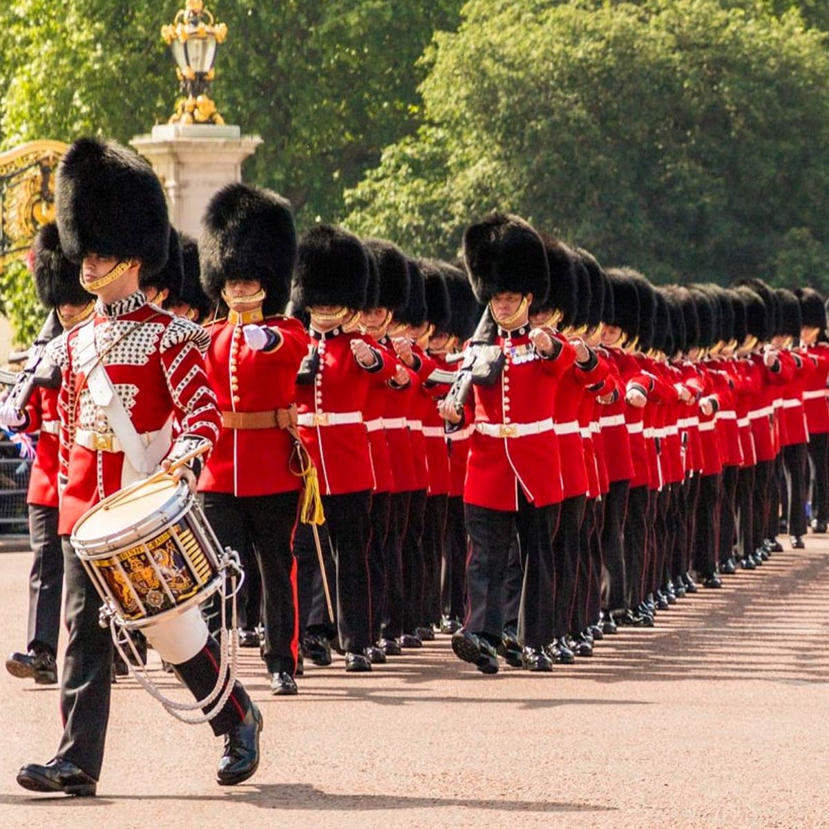 British guards in red uniforms and bearskin hats marching in parade formation