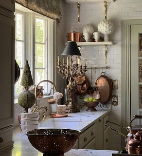 Elegant Christmas kitchen with copper pots, candelabra, topiary decor, and white subway tile backsplash