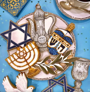 Decorated Hanukkah cookies with menorahs, dreidels, and Stars of David on blue background