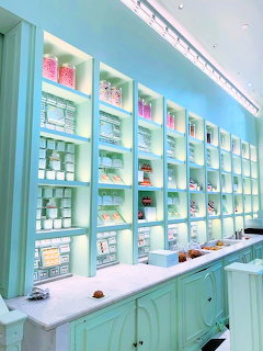Pastel mint cafe interior with illuminated shelves holding cups, boxes, and pastries