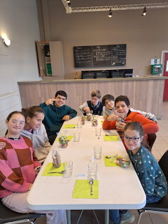 Six children seated around a long table in a cafe or restaurant.