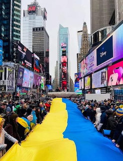 Crowds in Times Square surround a giant blue and yellow Ukraine flag in New York City