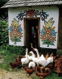 Painted cottage with floral murals on walls and geese and chickens at the entrance in Zalipie, Poland